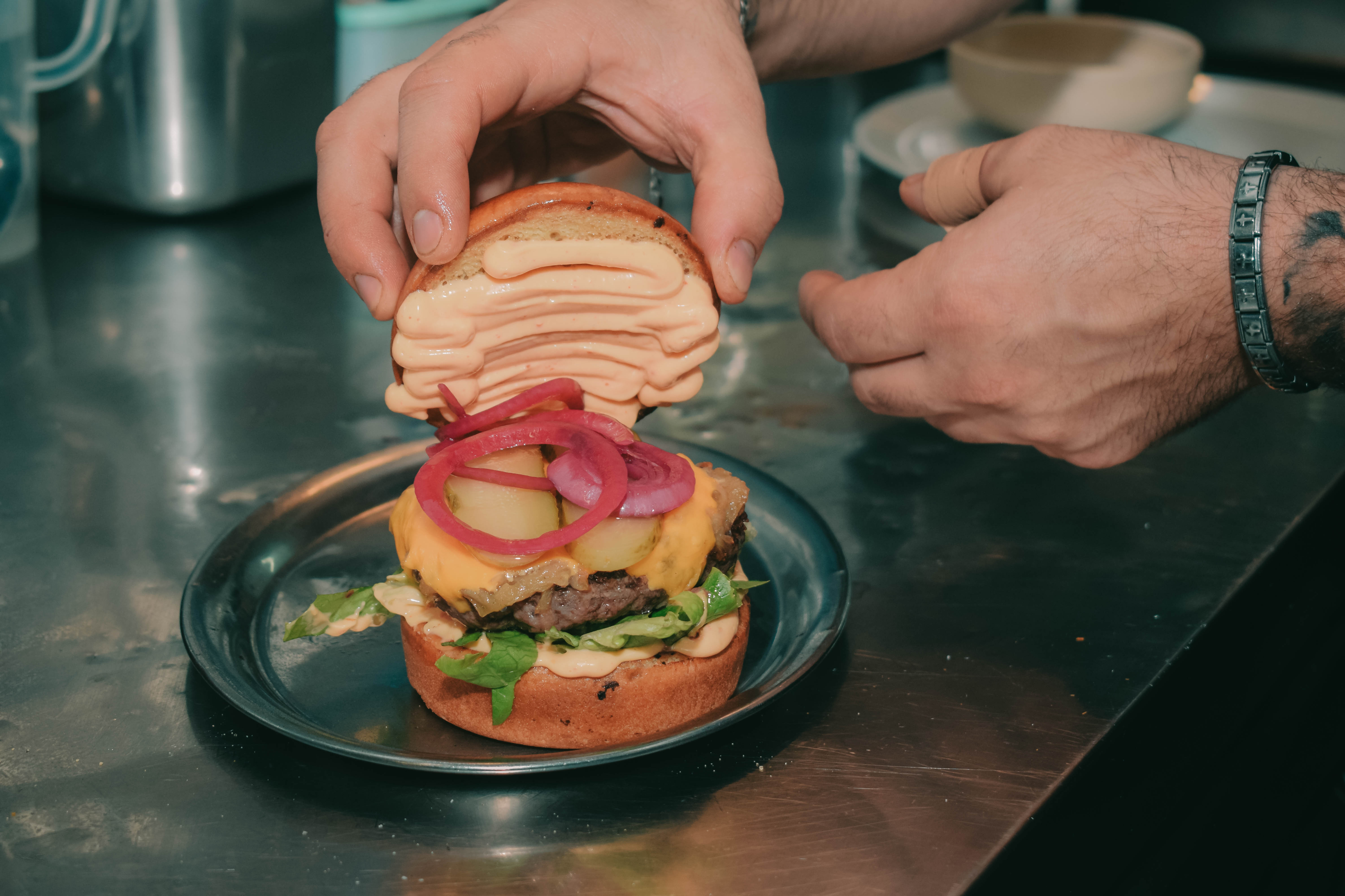 Saftiger Beef Burger mit hausgemachter Käsesauce, Sriracha-Mayo und knusprigen Pommes